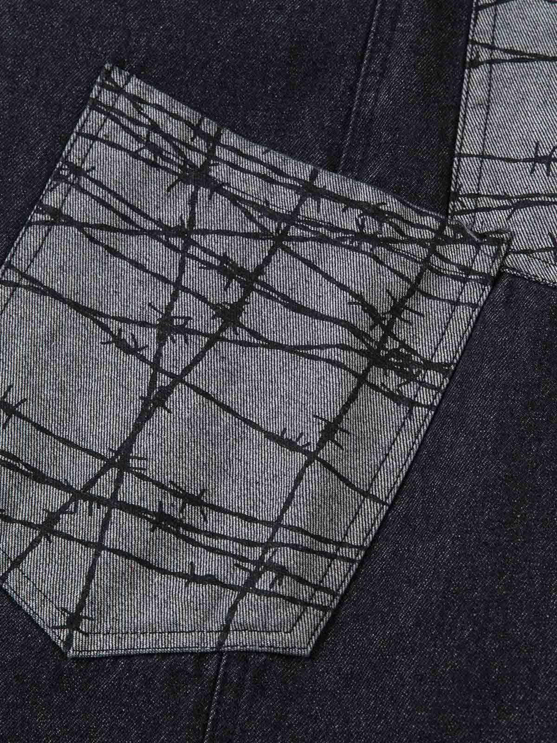 Intricate barbed wire pattern on TALISHKO baggy jeans' patch pocket, highlighting unique style.