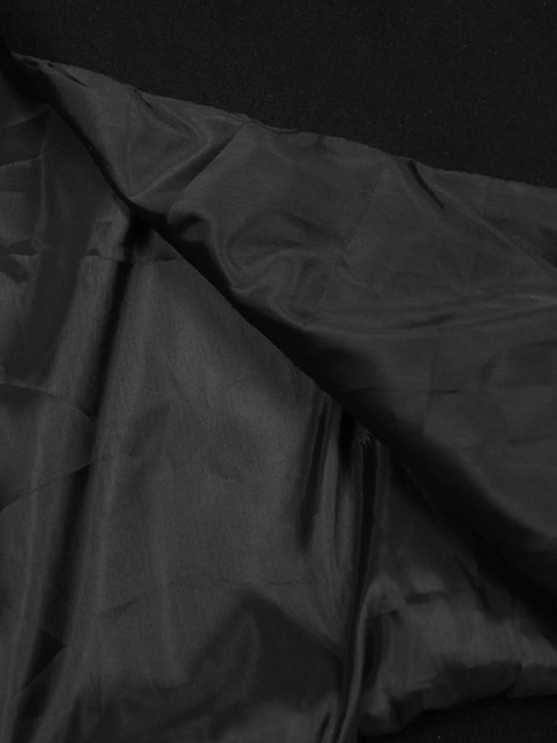 Detailed fabric and stitching of TALISHKO's baseball jacket highlighting contrast patchwork design.