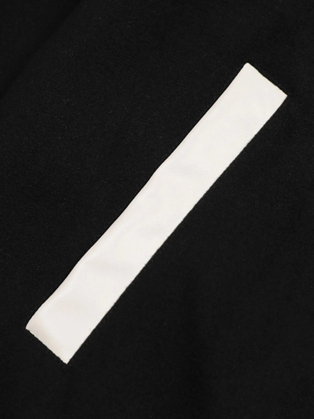 A detailed view of TALISHKO's baseball jacket highlighting the contrast patchwork design.