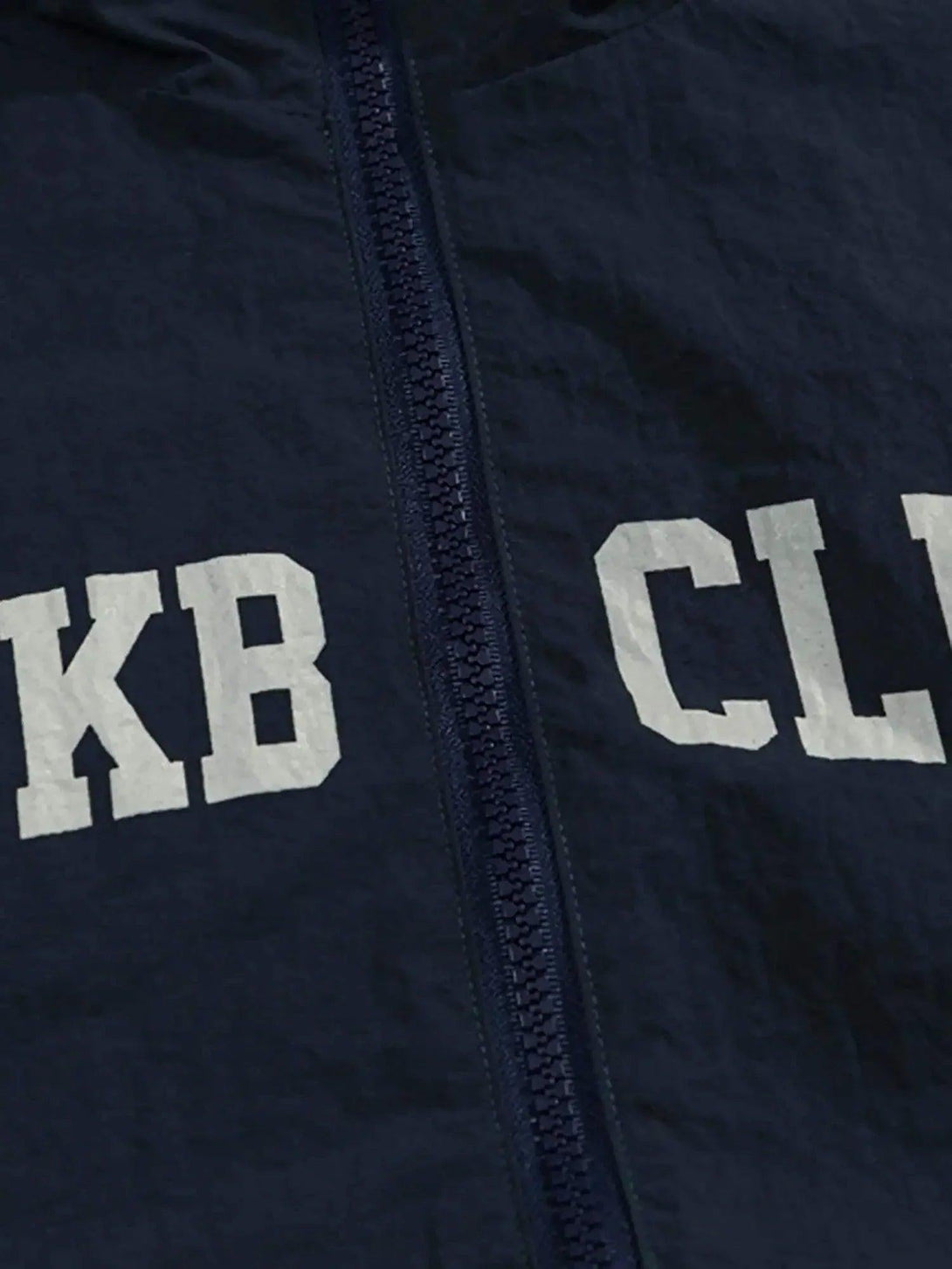 A detailed view of a TALISHKO windbreaker jacket's front zipper, highlighting bold lettering.