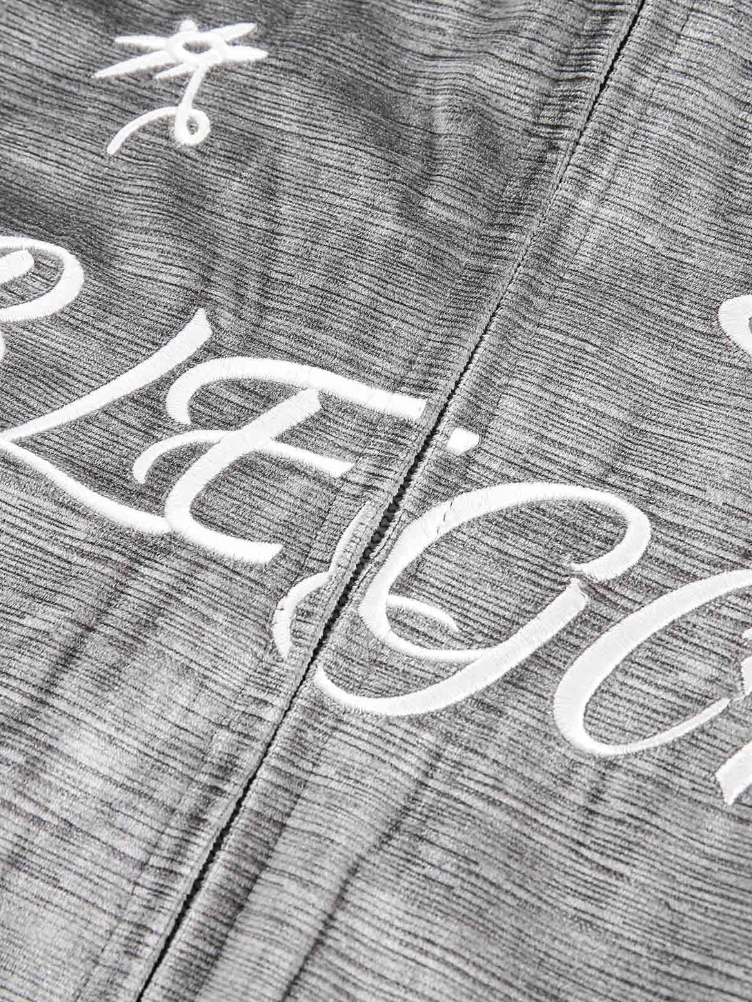 Intricate embroidery detail on gray patchwork bomber jacket by TALISHKO, highlighting texture.