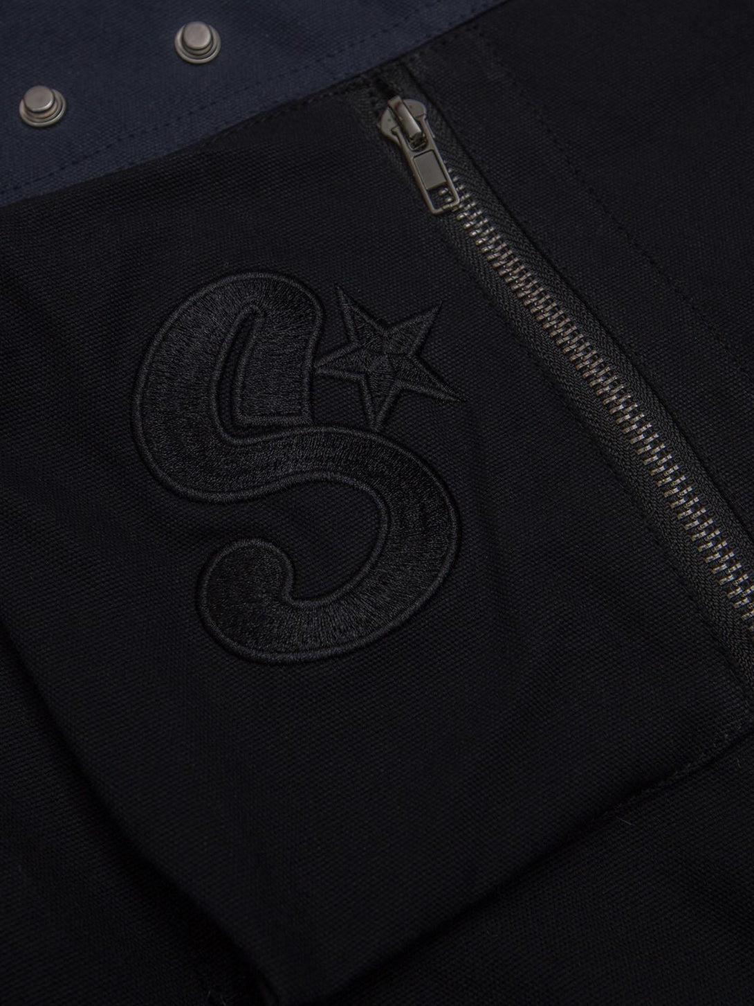 A detailed view of the embroidered "S" and star on a TALISHKO jacket, highlighting craftsmanship.