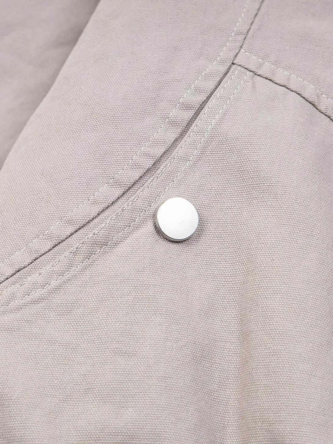Intricate look at TALISHKO's quilted jacket fabric and stitching, featuring a sleek button detail.