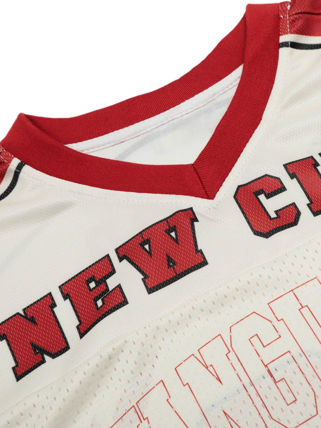 Focusing on the neckline detail of the TALISHKO patchwork mesh jersey T-shirt with bold lettering.