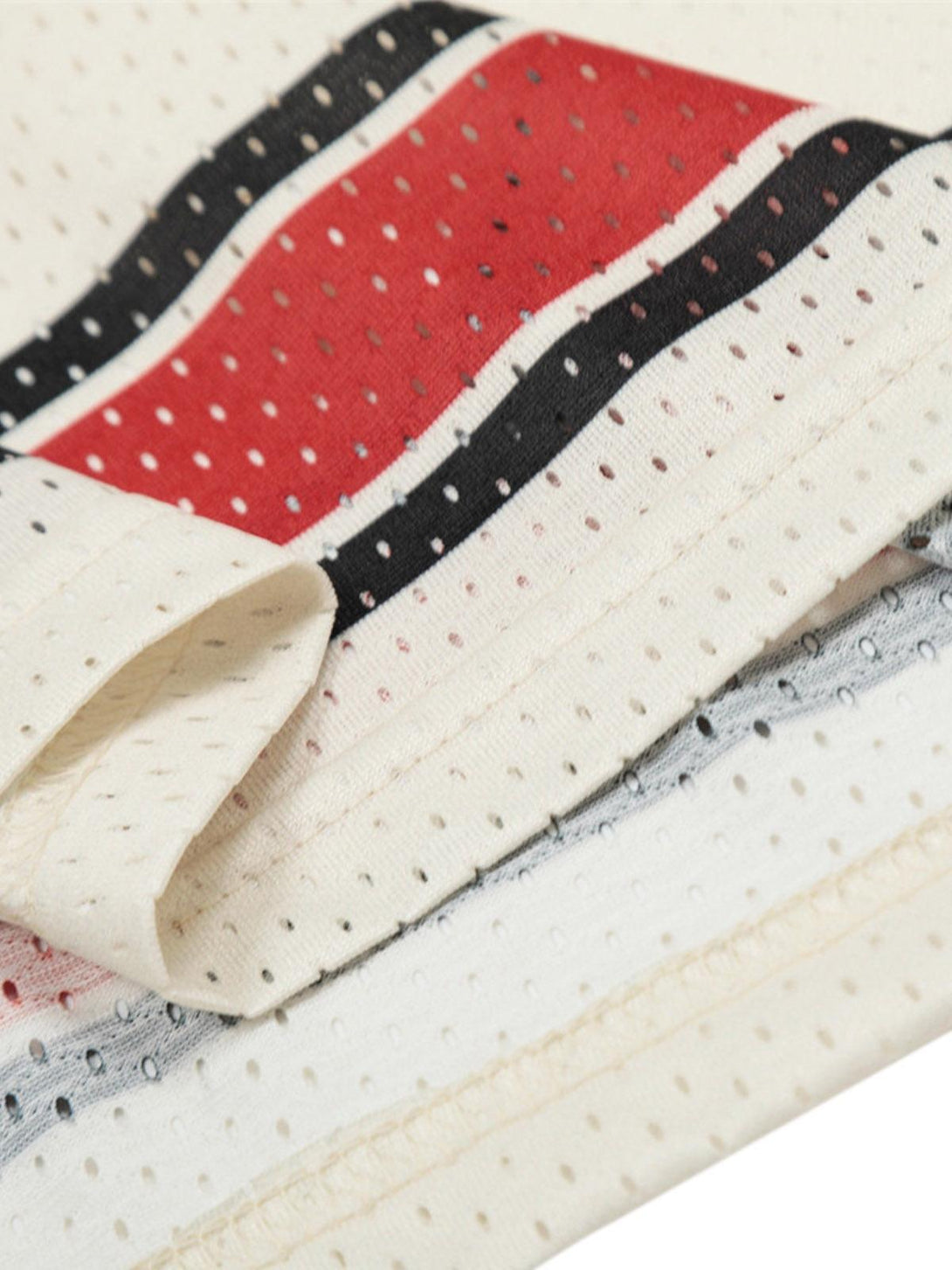 Detailed fabric and stitching of TALISHKO patchwork mesh jersey T-shirt with red and black stripes.