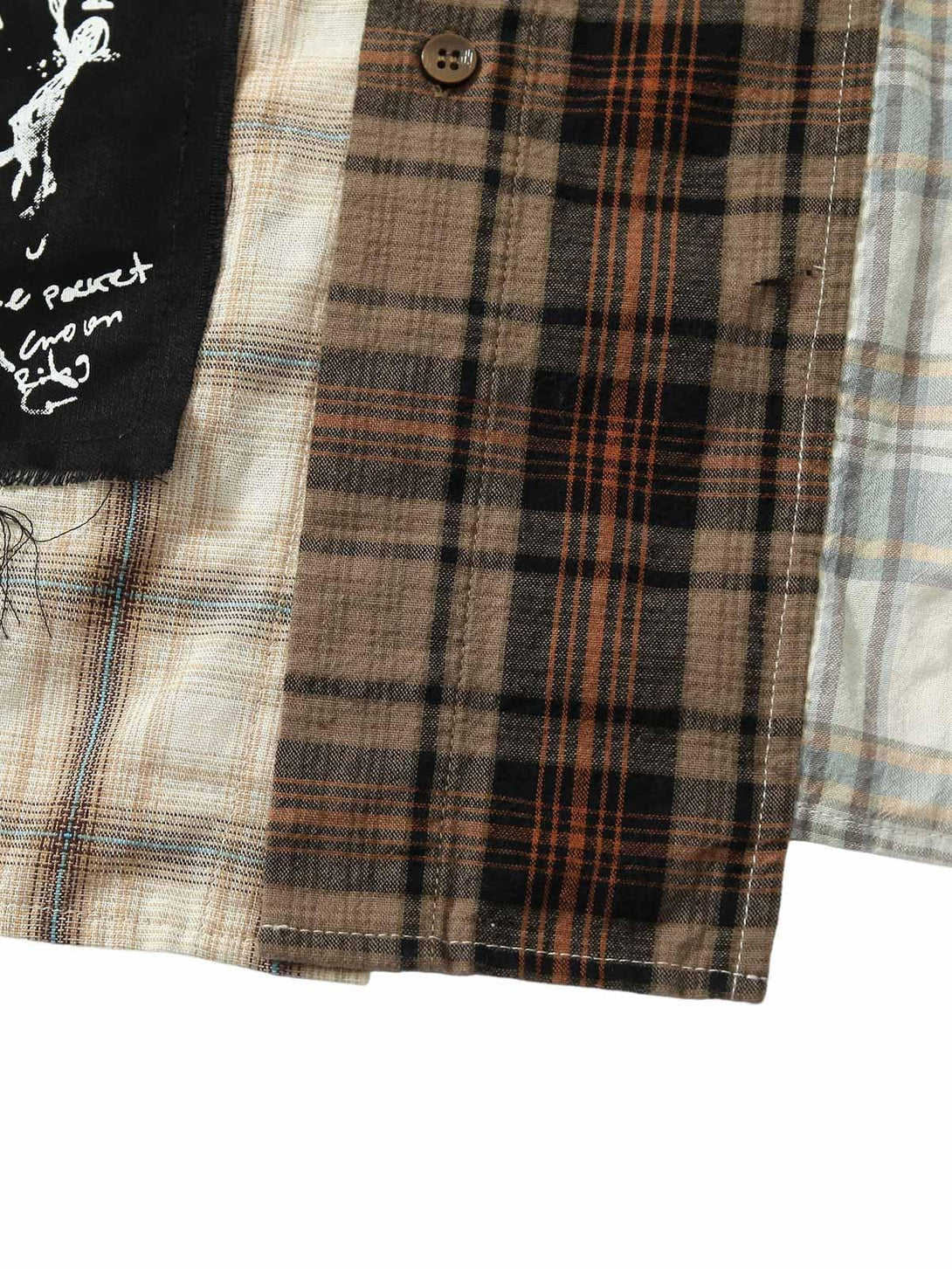 Intricate plaid patterns and stitching on TALISHKO's patchwork shirt, highlighting earthy tones.