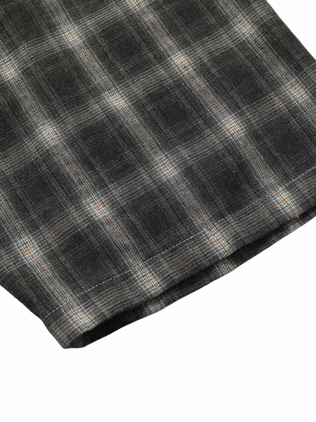 Intricate plaid texture on TALISHKO's short-sleeve shirt, highlighting detailed stitching.