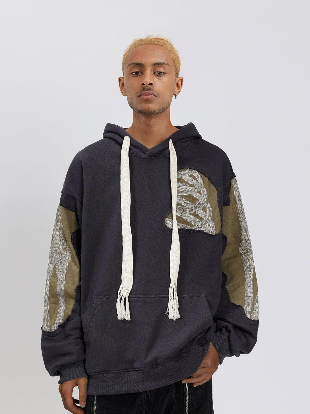 Model wearing a patchwork skeleton hoodie with unique designs by TALISHKO, styled casually.