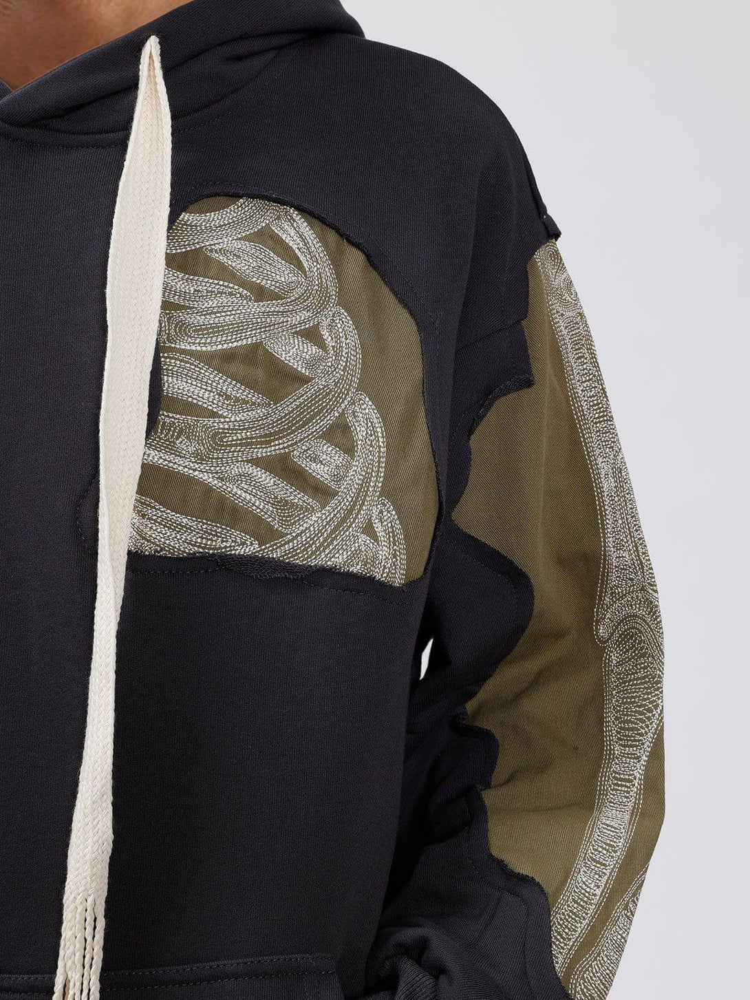 Intricate look at TALISHKO's patchwork skeleton hoodie, highlighting unique sleeve details.