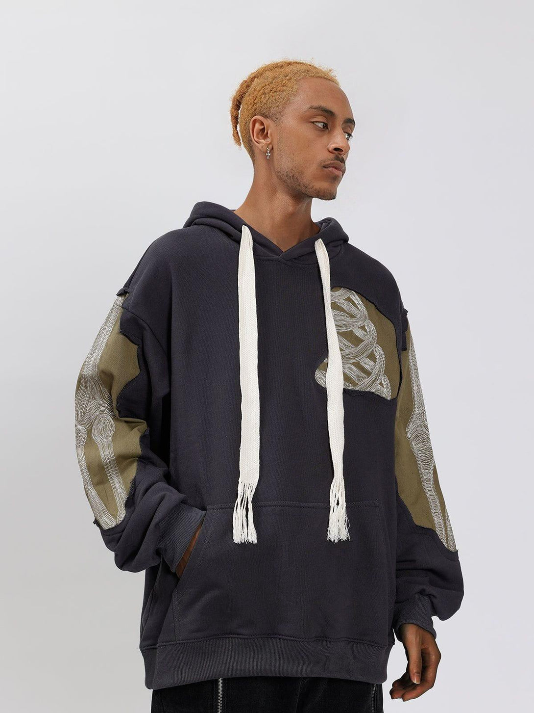 Model wearing TALISHKO patchwork skeleton hoodie with unique sleeve detailing, styled casually.
