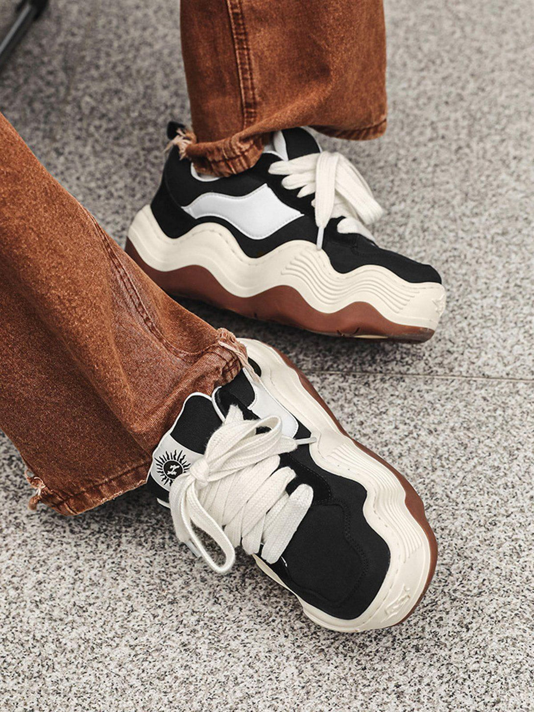 TALISHKO patchwork sneakers with thick wavy soles, styled with brown frayed jeans.