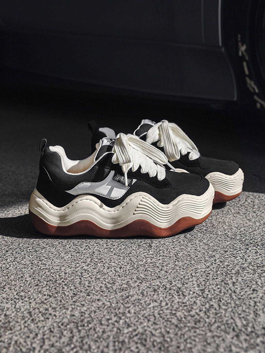 TALISHKO black sneakers with distinct thick wavy soles, perfect for a bold streetwear vibe.