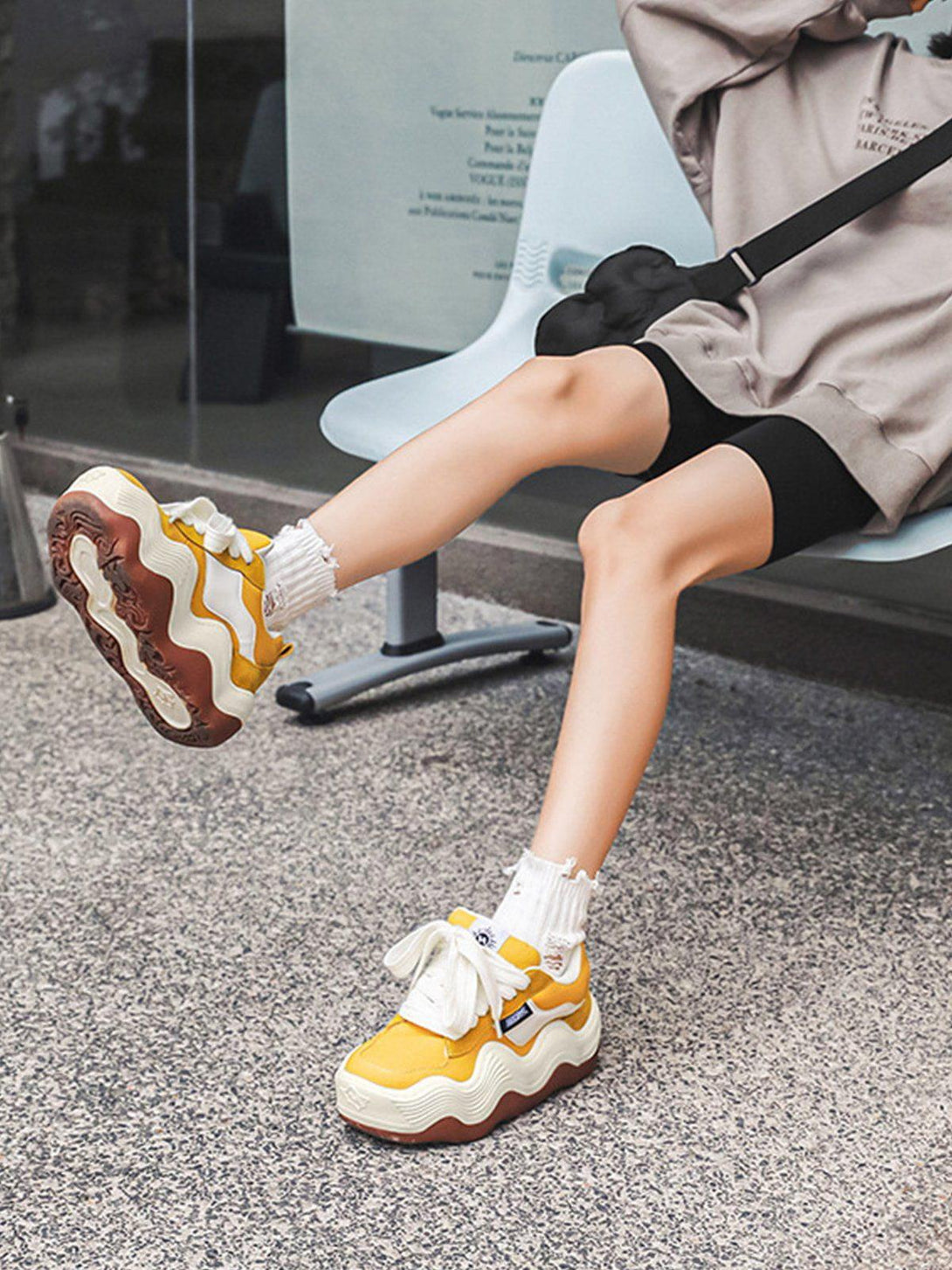 TALISHKO yellow sneakers with thick wavy soles, paired with casual shorts and a hoodie.