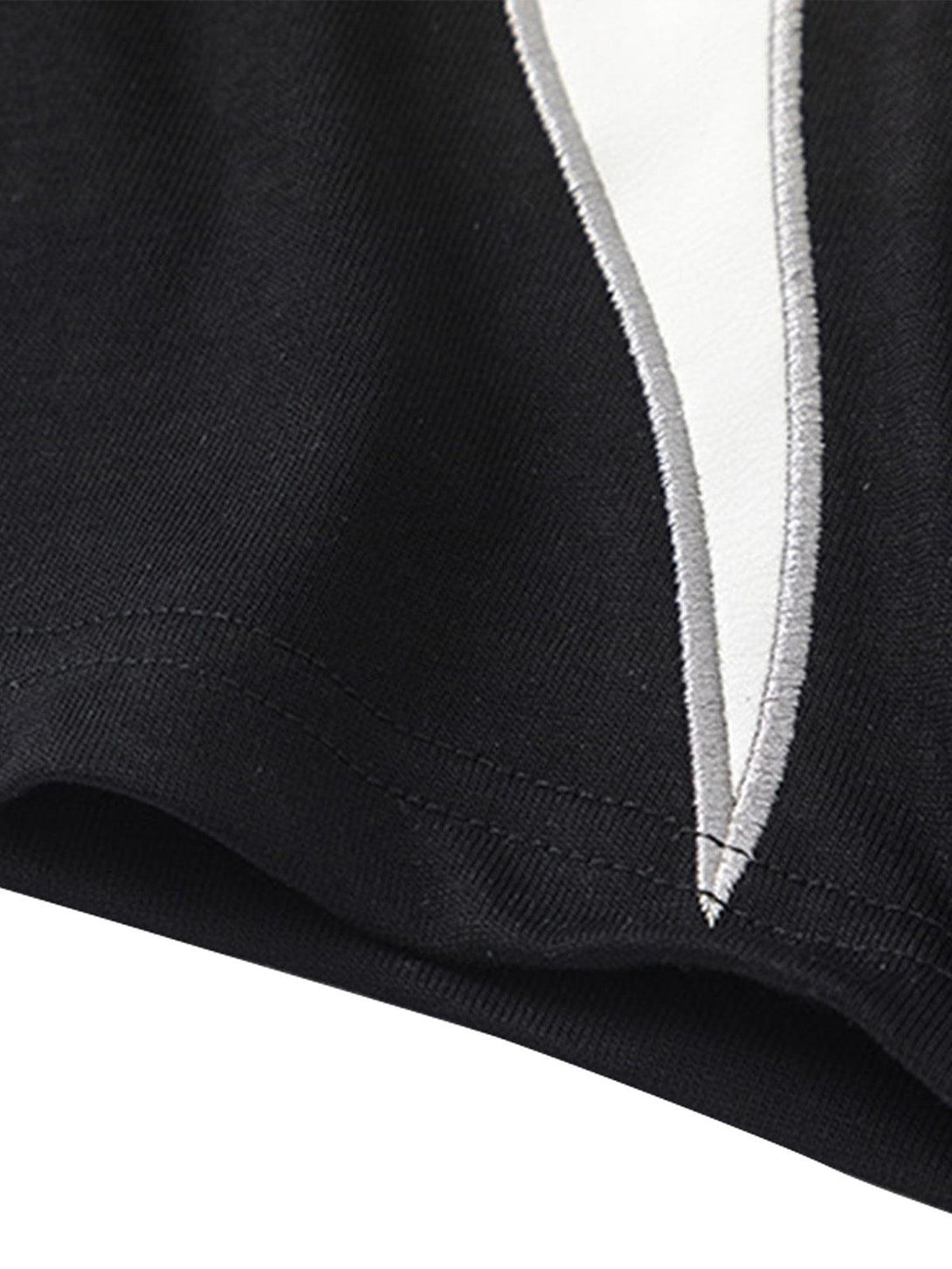 A close-up of the Patchwork Totem T-shirt by TALISHKO, featuring detailed black and white stitching.