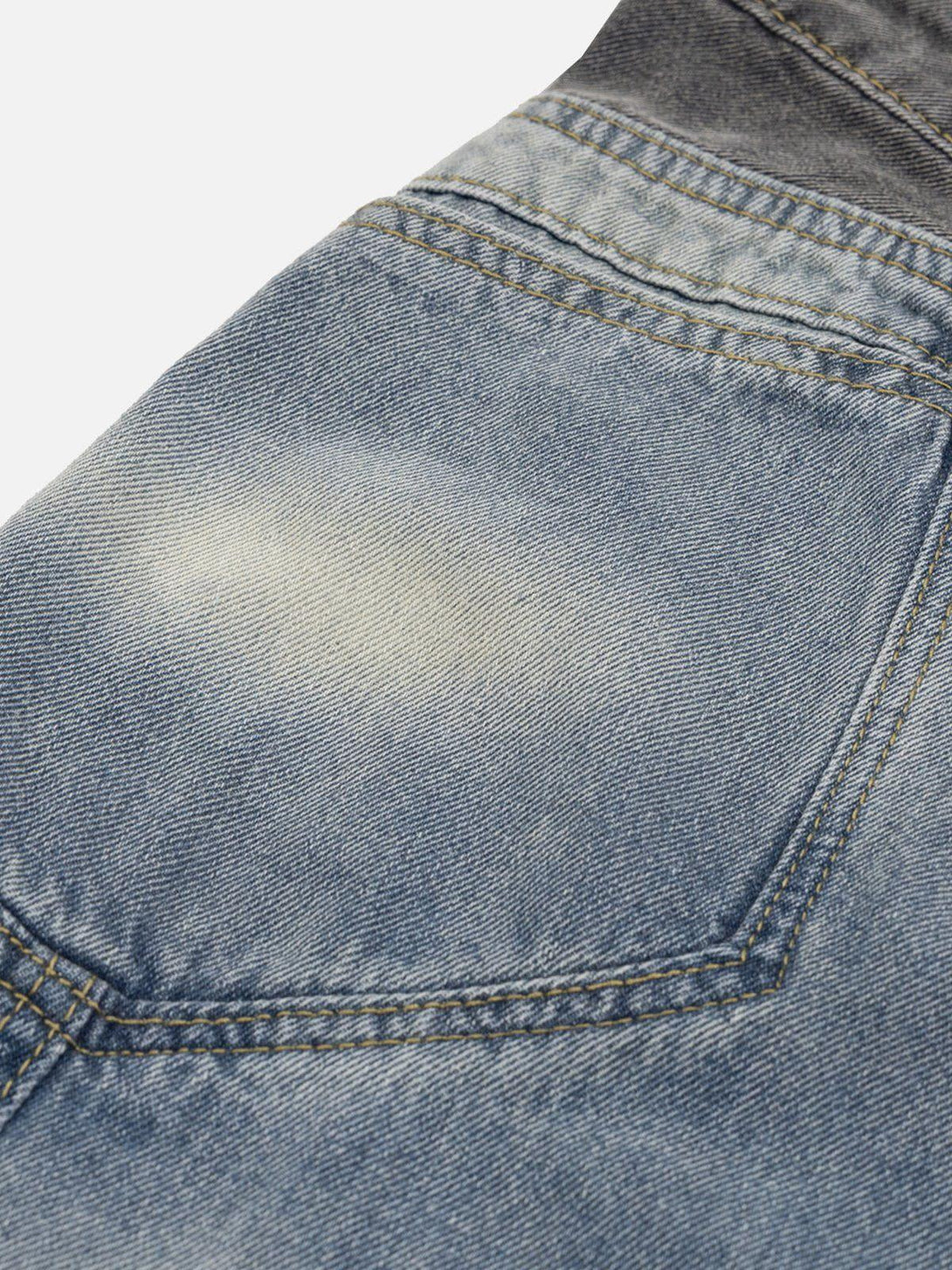 A detailed view of TALISHKO's patchwork waist on loose jeans, showcasing the unique wrinkle texture.