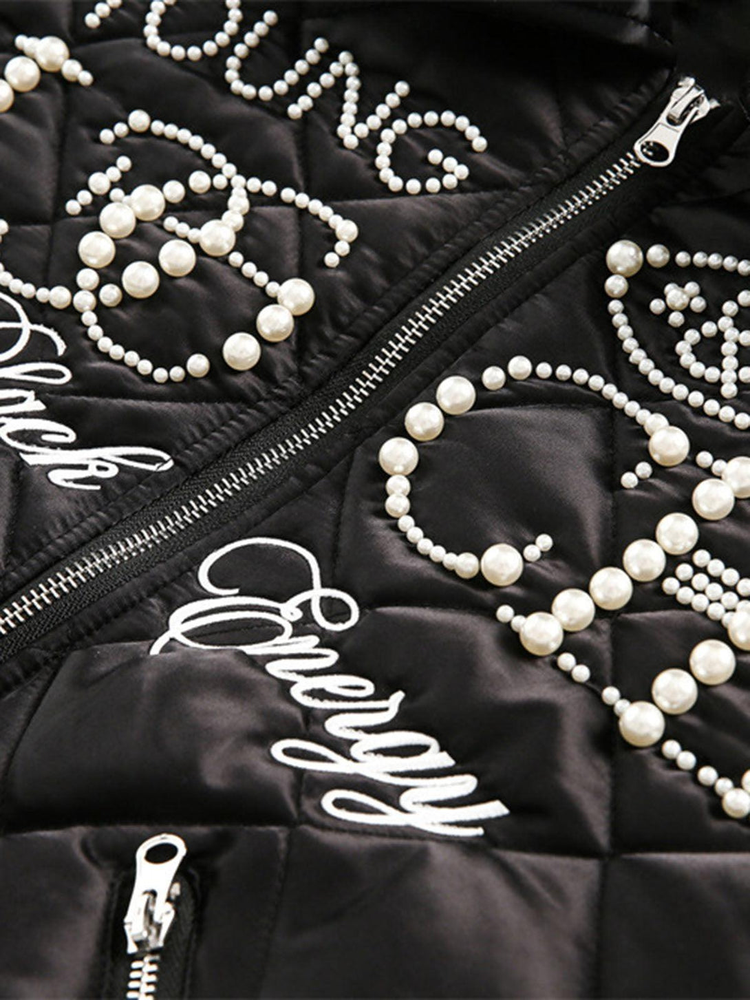 Intricate look at the pearl lettering on TALISHKO's black quilted jacket, emphasizing modern elegance.