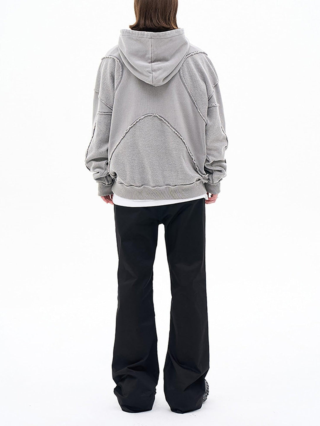 Back view of gray TALISHKO hoodie with unique design details, styled with black pants.