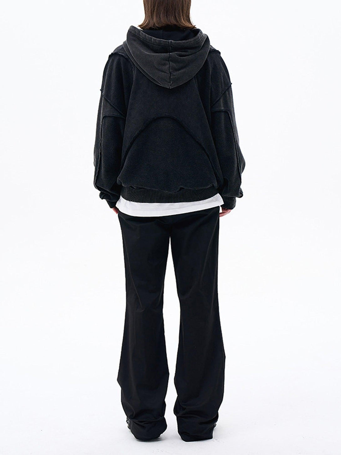 Back view of TALISHKO's black hoodie, featuring a unique design, styled with relaxed black pants.