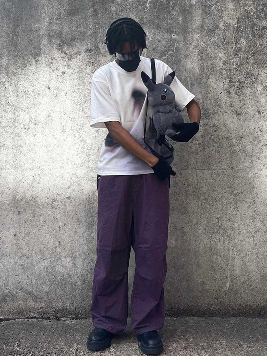 Model wearing a white TALISHKO T-shirt with phantom print, styled with purple pants and accessories.