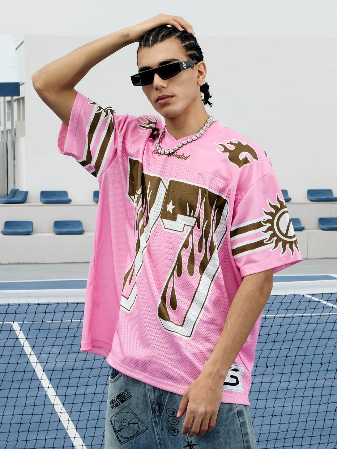 Model in TALISHKO pink flame print jersey T-shirt, wearing sunglasses and casual denim.