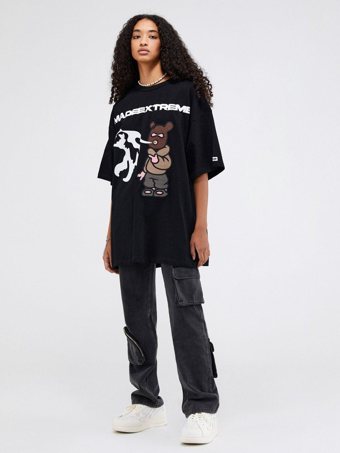Model in a black TALISHKO graphic tee with playful bear design, paired with cargo pants.