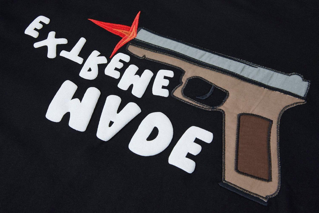 TALISHKO tee showcasing a bold pistol graphic and playful text on a black fabric close-up.