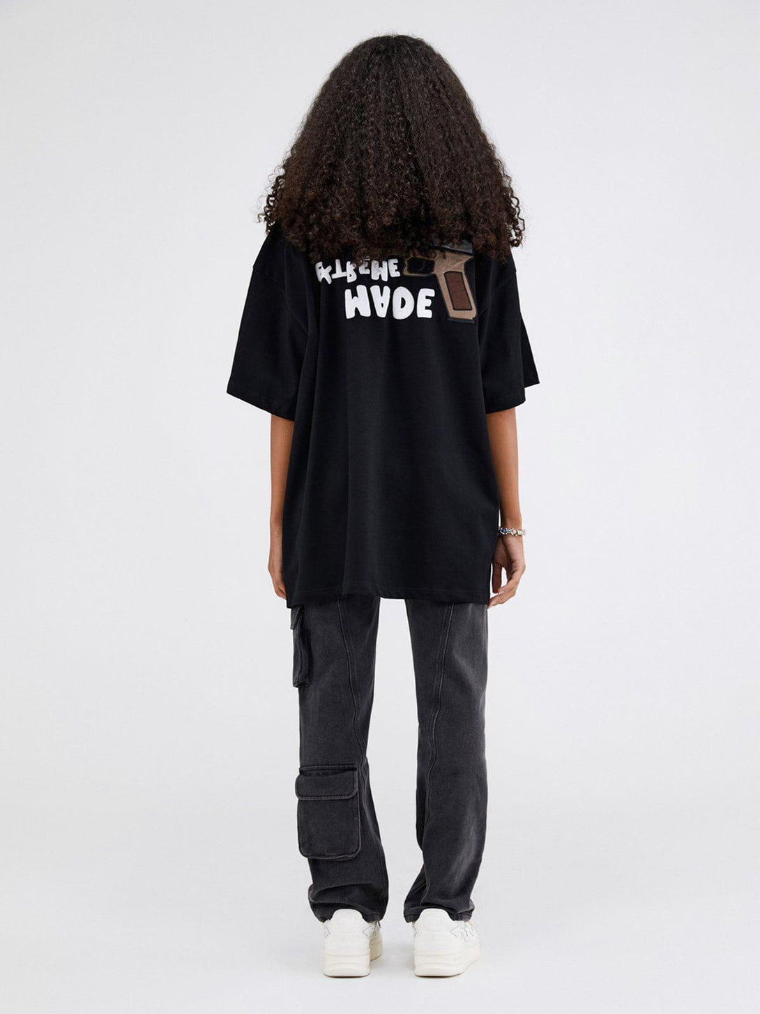 Back view of black TALISHKO tee with bold graphic and text, paired with cargo pants.