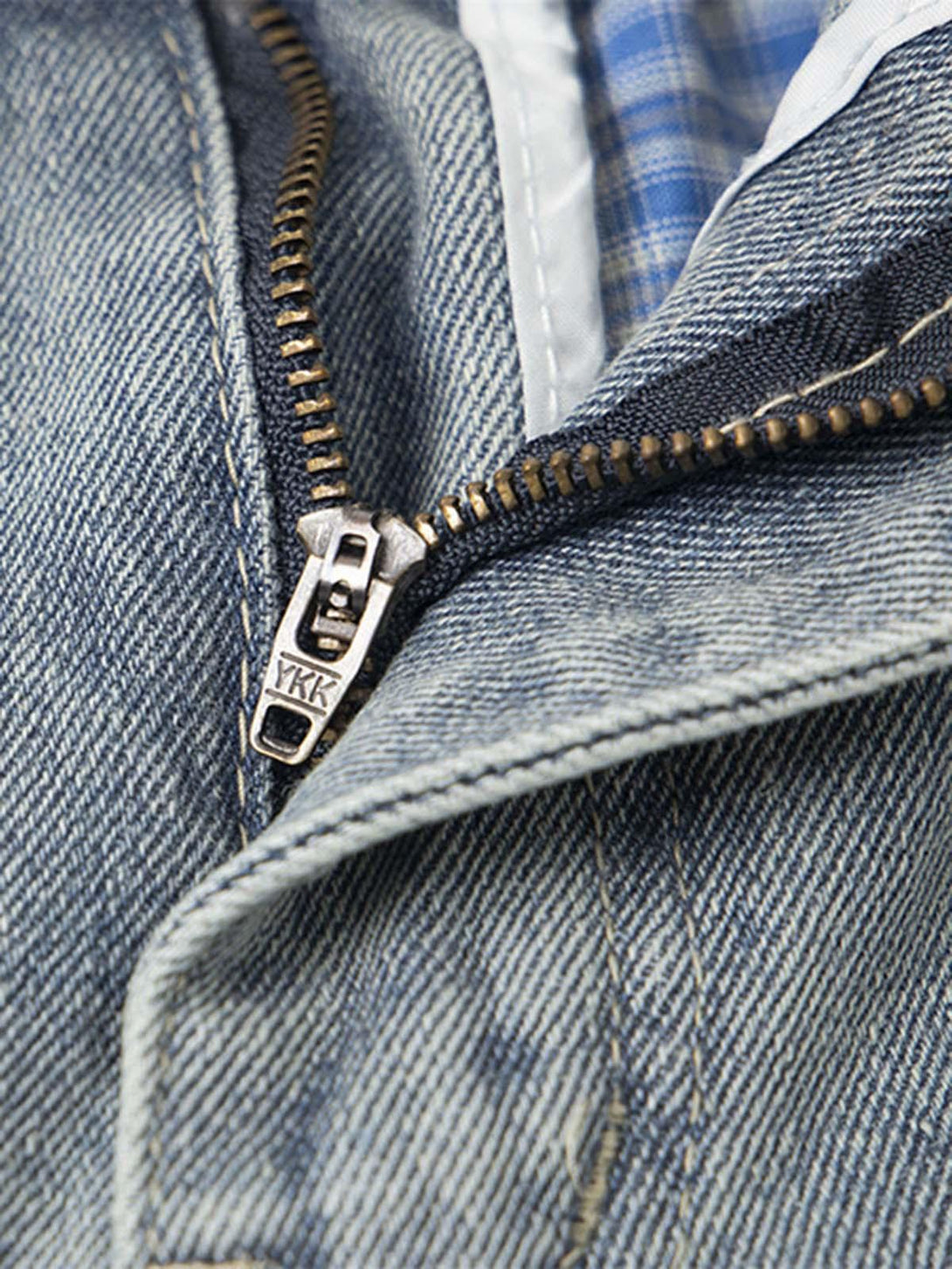 A close-up of TALISHKO baggy jeans zipper, highlighting denim texture and plaid lining.