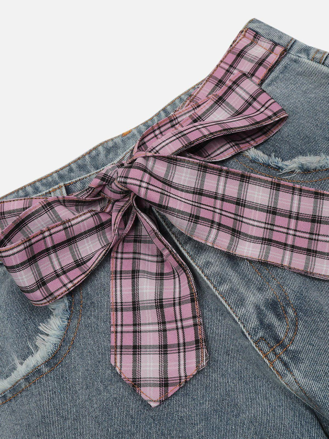 A detailed view of TALISHKO jeans with pink plaid bow and patchwork, highlighting unique design.