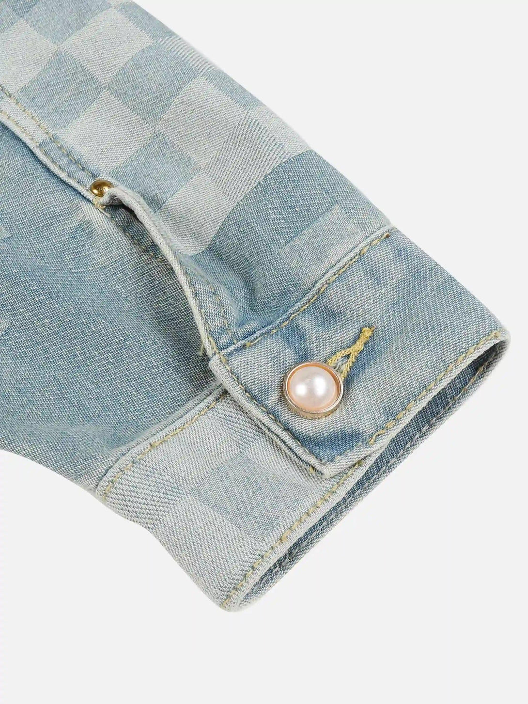 Intricate look at TALISHKO's denim jacket cuff with plaid pattern and pearl button detail.