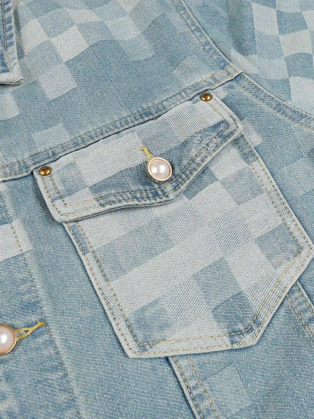 Zoomed-in texture of TALISHKO's plaid denim jacket, highlighting pearl button detail.