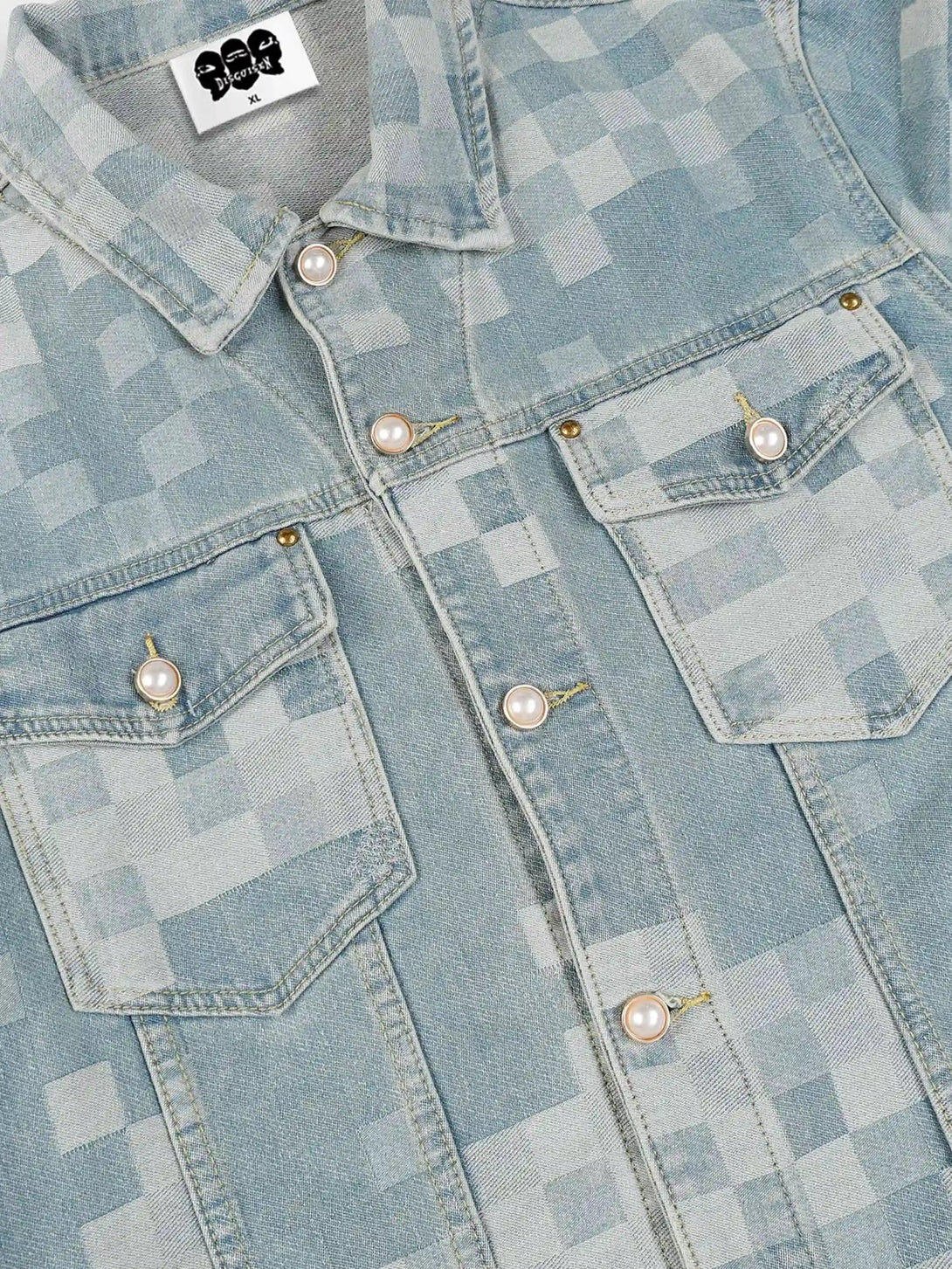 Focusing on the plaid pattern and pearl buttons of TALISHKO's denim jacket in a detailed view.