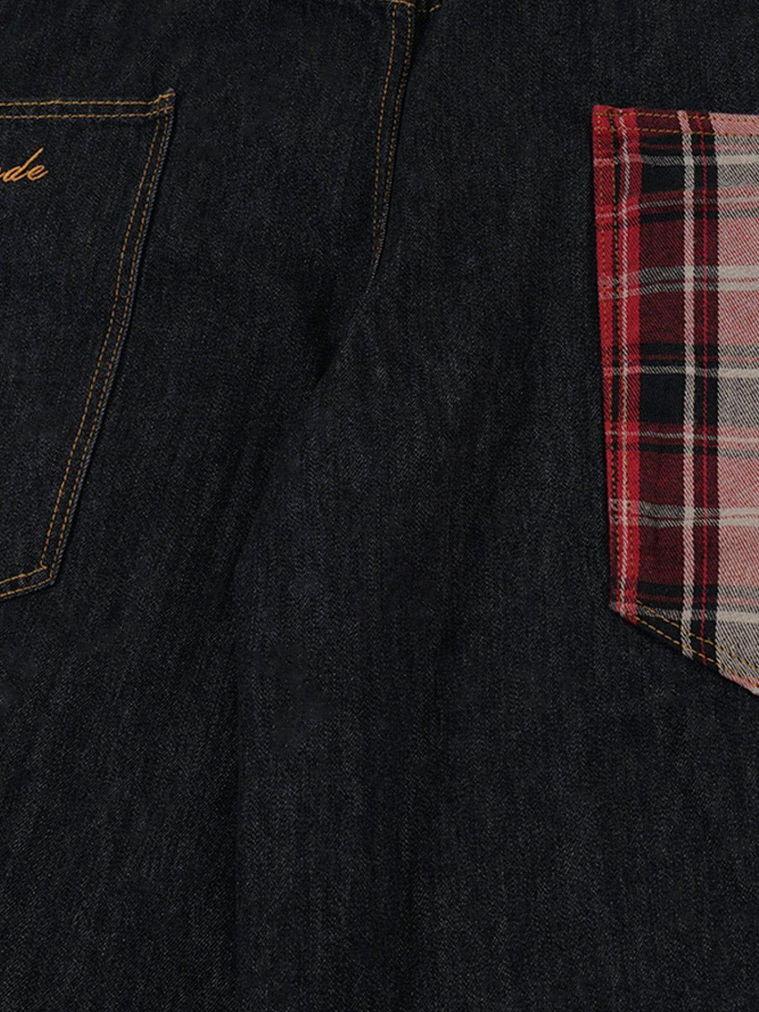 Detailed view of TALISHKO jeans showcasing plaid pocket contrast with dark denim fabric.