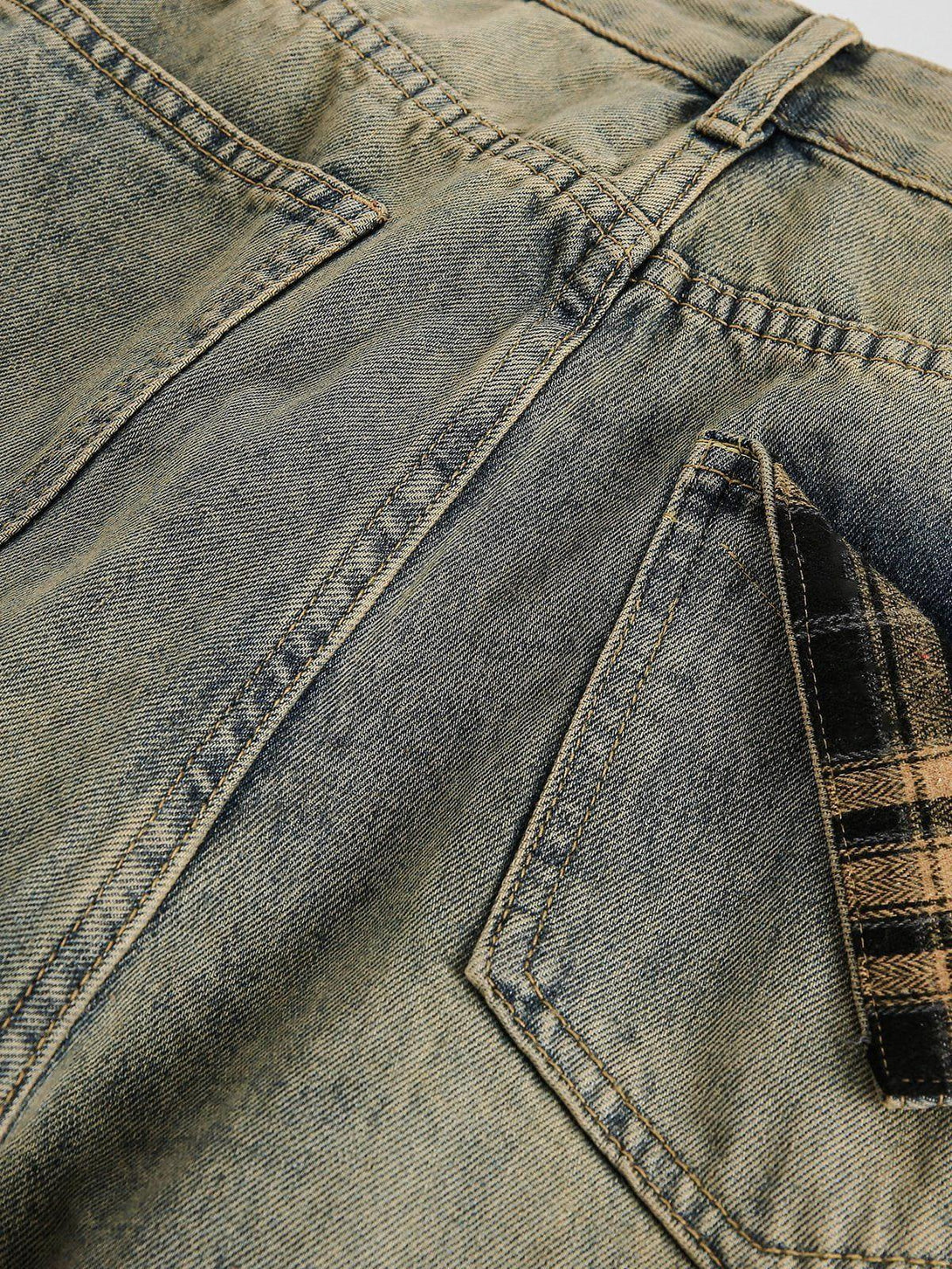 A close-up of TALISHKO jeans featuring a plaid pocket and vintage wash detail.