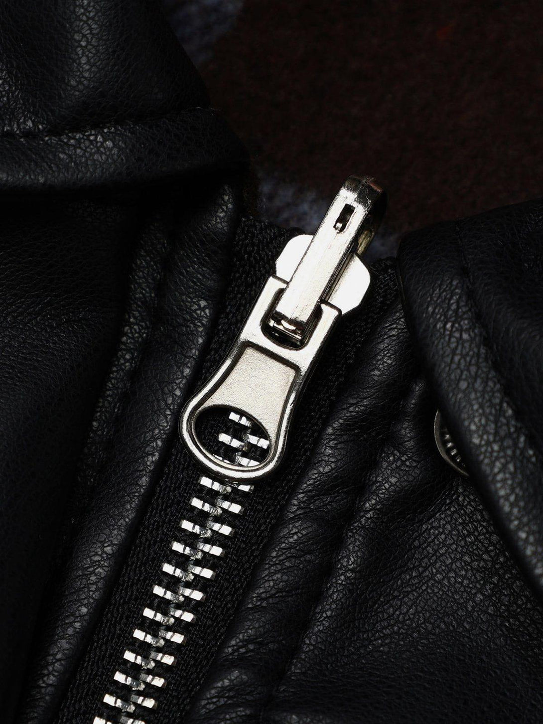 A close-up of TALISHKO's black leather jacket zipper, showcasing sleek craftsmanship.