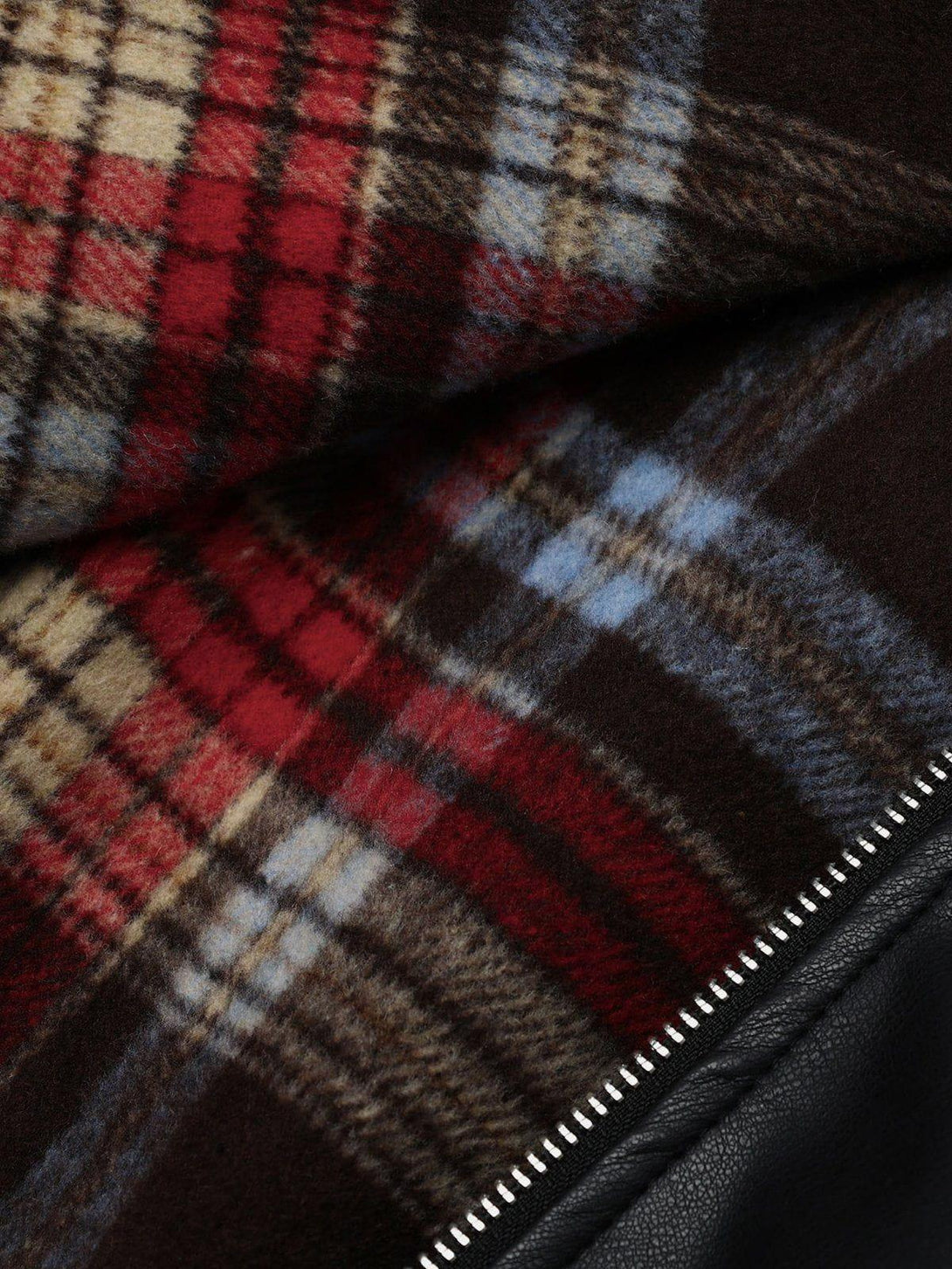 Plaid pattern and leather texture of TALISHKO jacket, highlighting intricate fabric details.