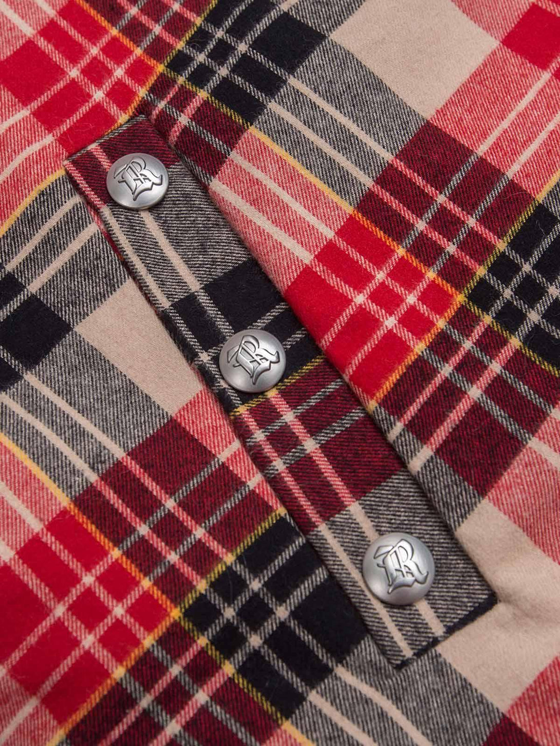 Intricate look at TALISHKO's plaid fabric with button detail, showcasing classic style craftsmanship.