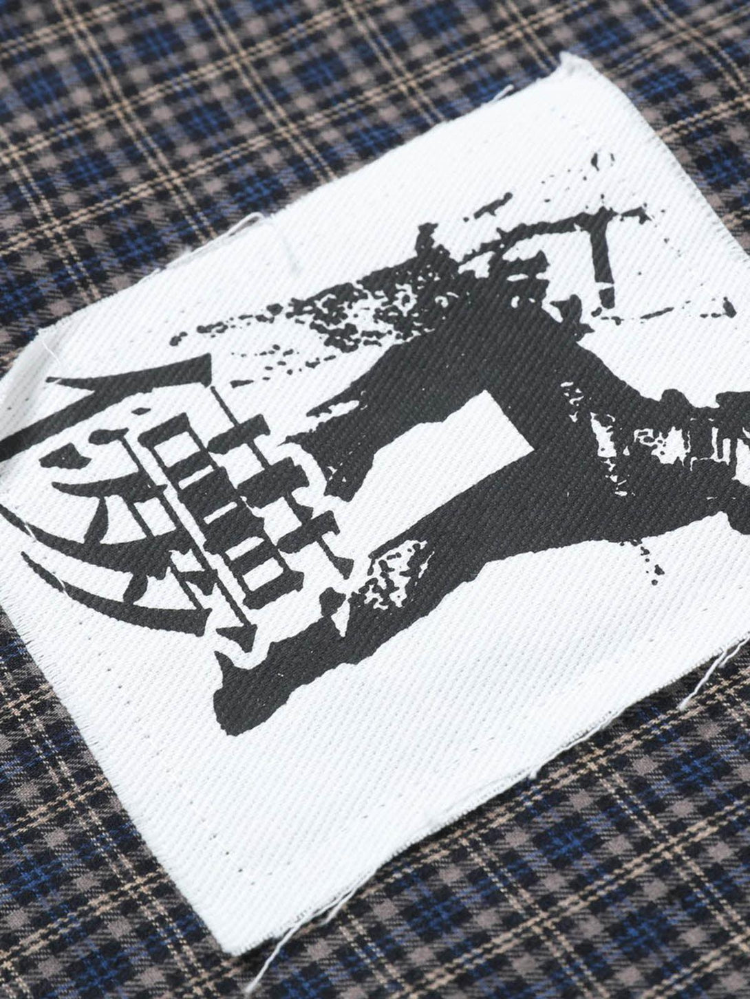 Zoomed-in texture of TALISHKO plaid shirt highlighting unique patch design.