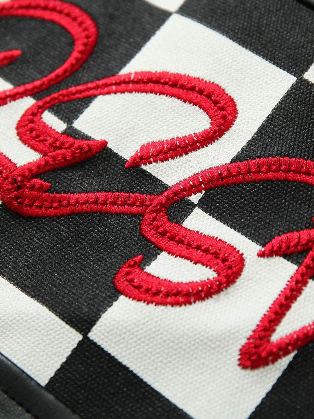 Zoomed-in texture of TALISHKO's jacket, showcasing checkered pattern and red embroidery detail.