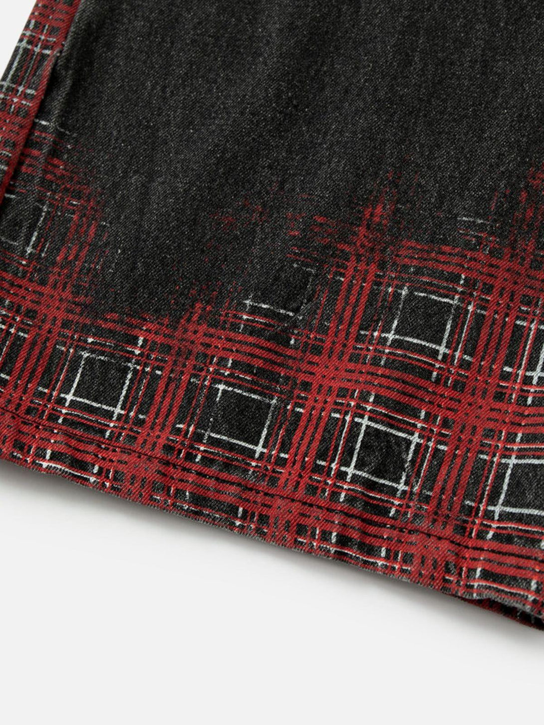 Zoomed-in texture of TALISHKO loose jeans showcasing red plaid pattern and washed design.