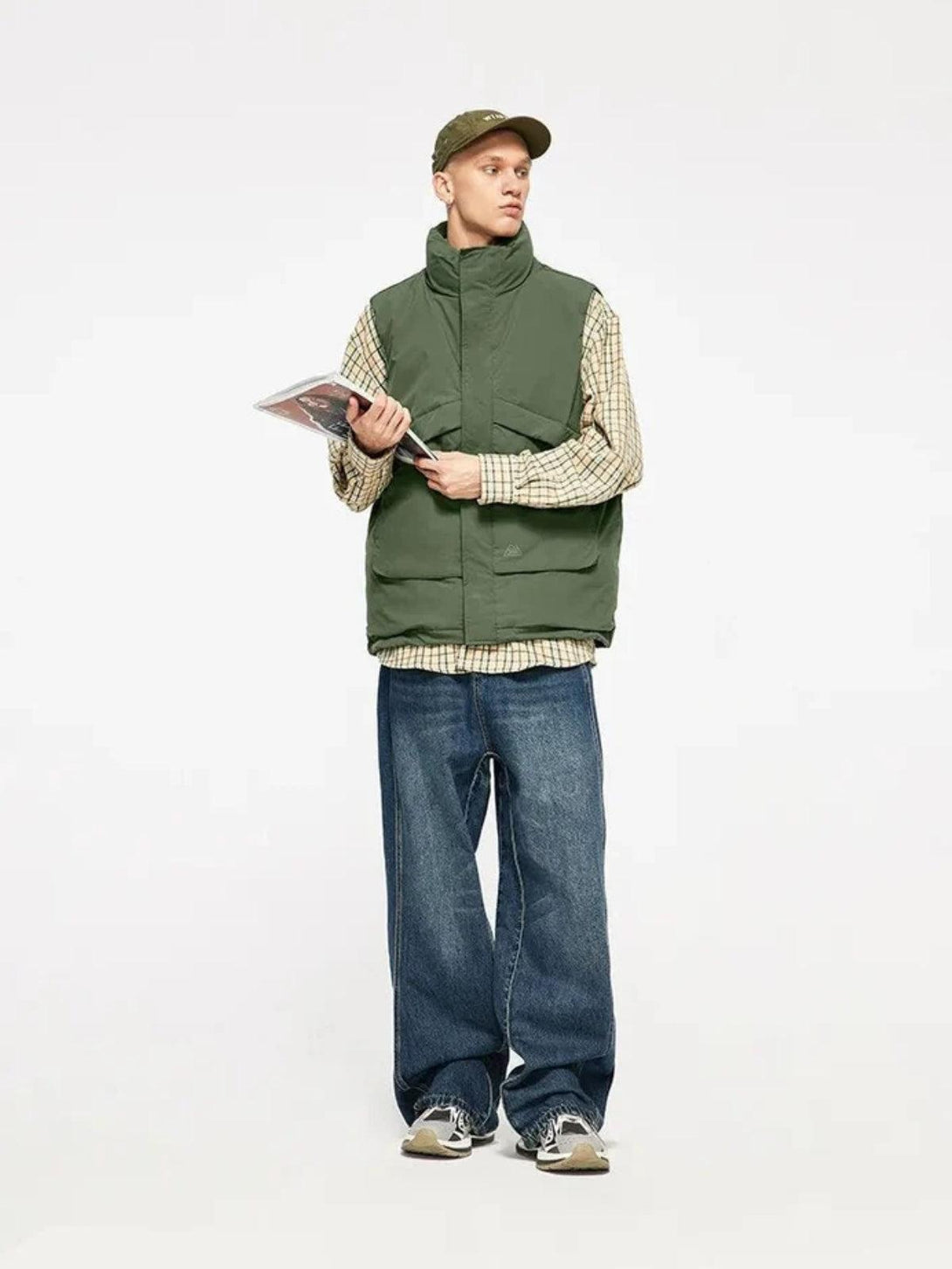 Model in a TALISHKO windproof vest, styled with plaid shirt, wide jeans, and a cap.