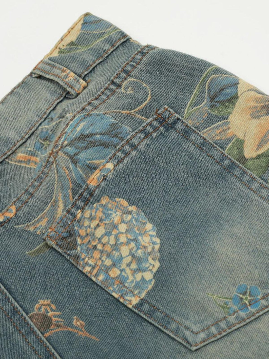 Intricate floral patterns on TALISHKO jeans pocket, showcasing detailed botanical design.