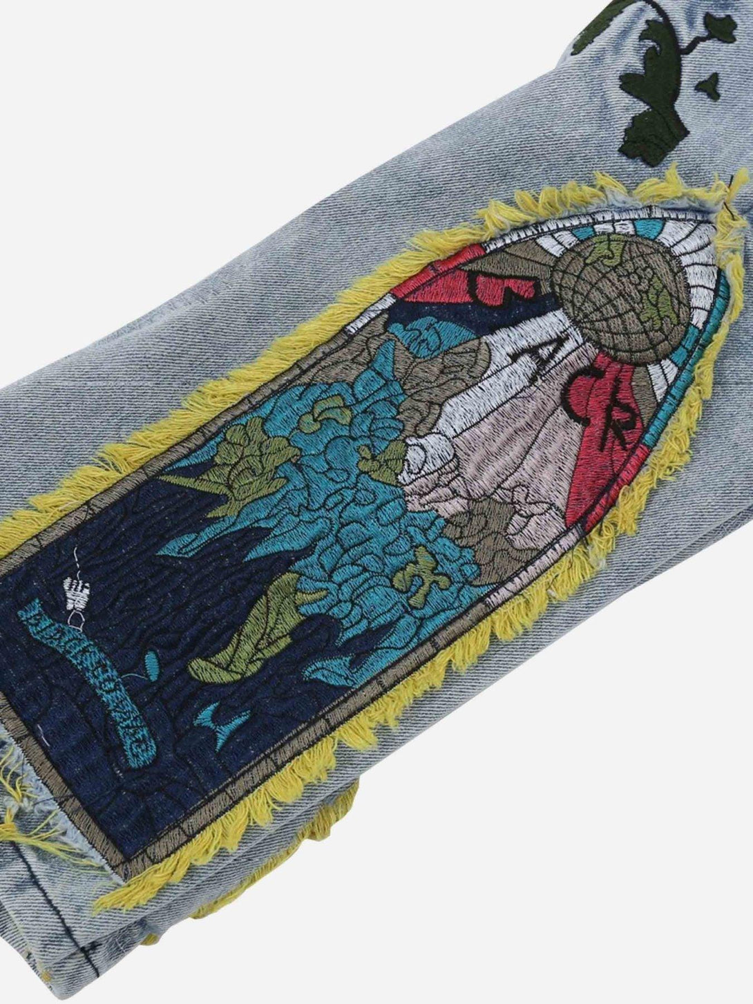 Intricate look at TALISHKO jeans with vibrant embroidery and yellow fringe details.