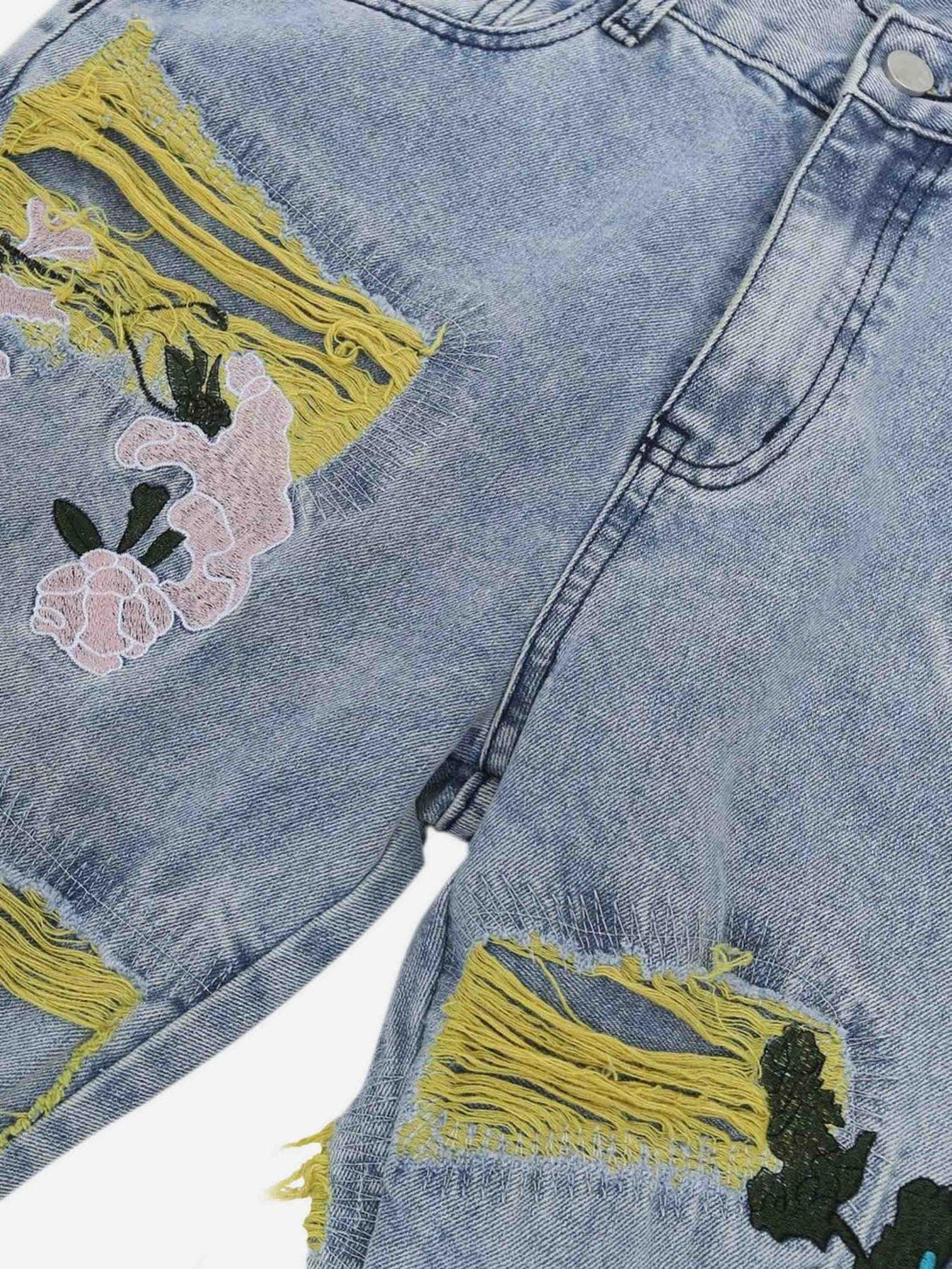 TALISHKO jeans featuring floral embroidery and yellow fringe distressing in a detailed view.
