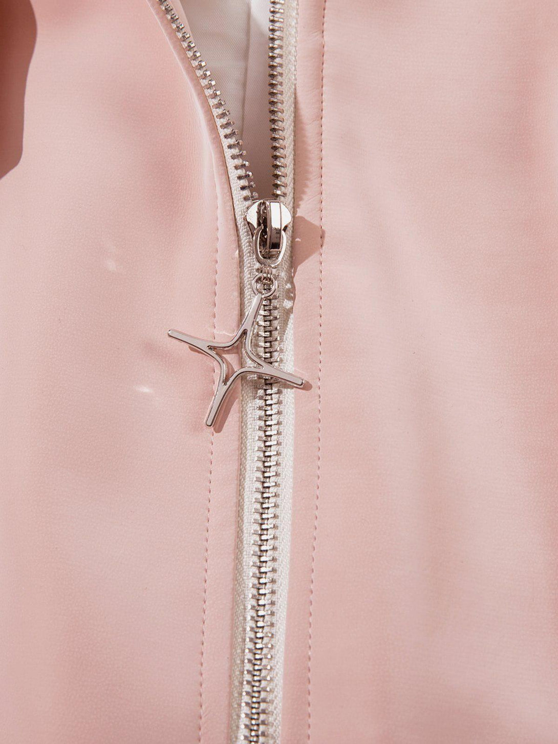 A detailed view of the silver zipper and pink suede texture on a TALISHKO faux leather jacket.