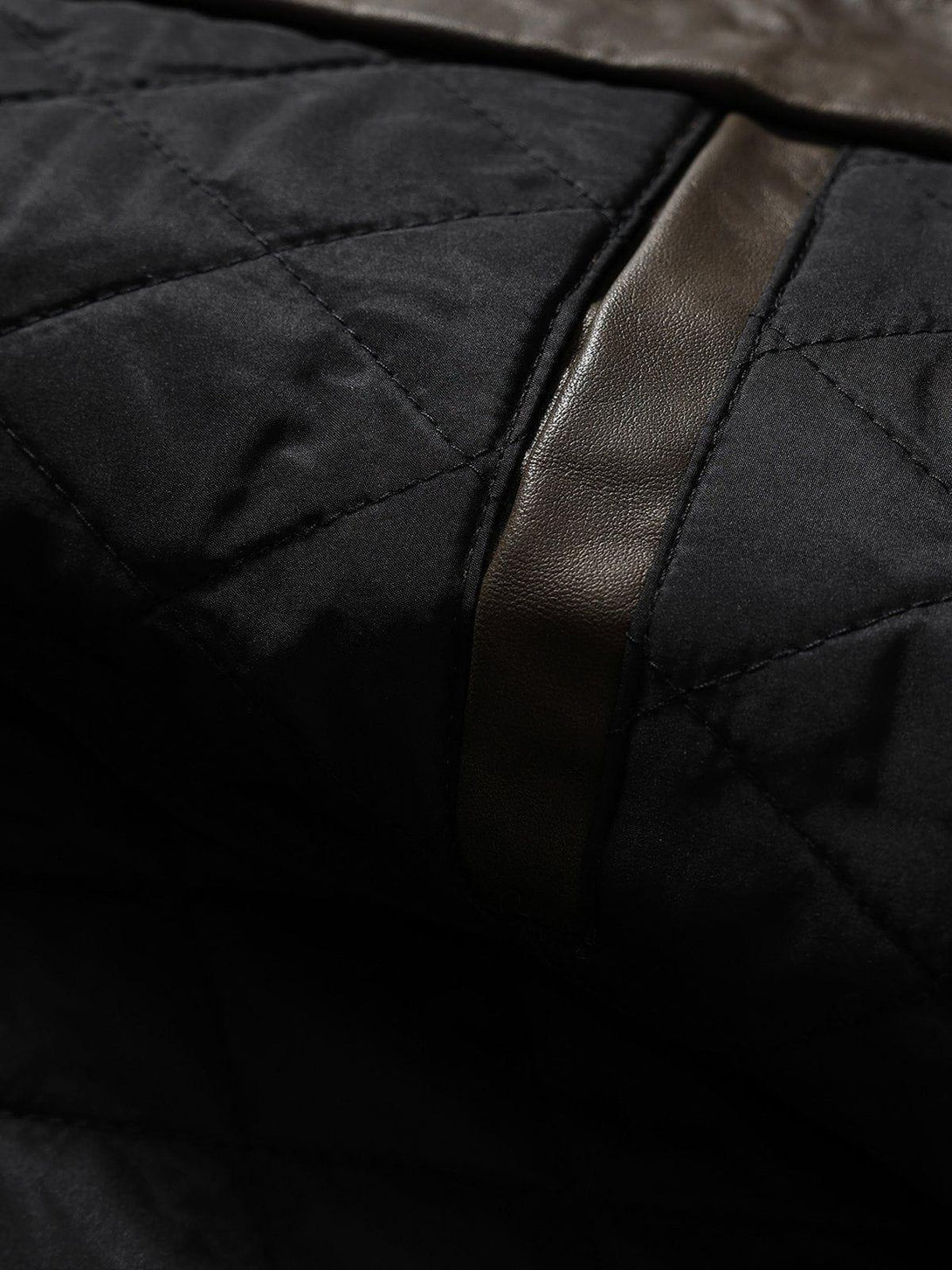 Intricate look at the quilted stitching and faux leather detail on TALISHKO's jacket.