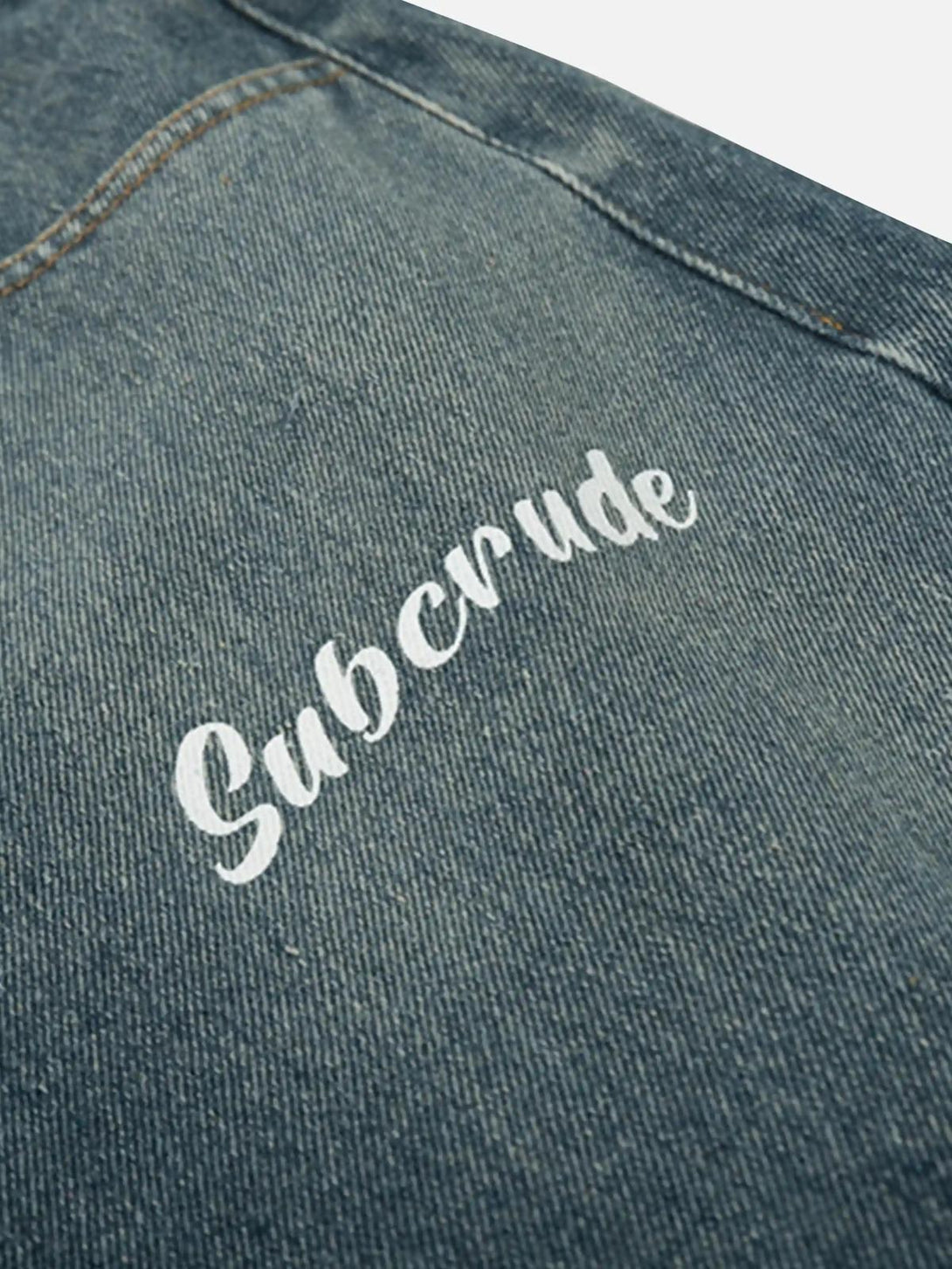 A detailed view of TALISHKO's washed jeans highlighting the unique "Subcrude" print design.