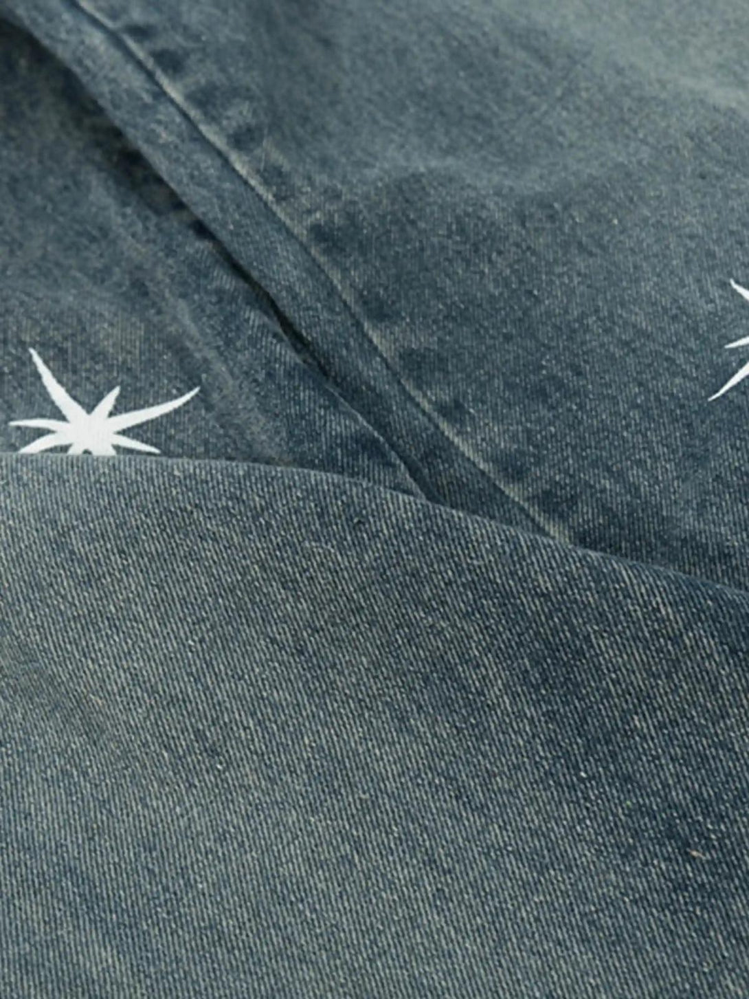 Zoomed-in texture of TALISHKO washed jeans with star print, showcasing unique style details.