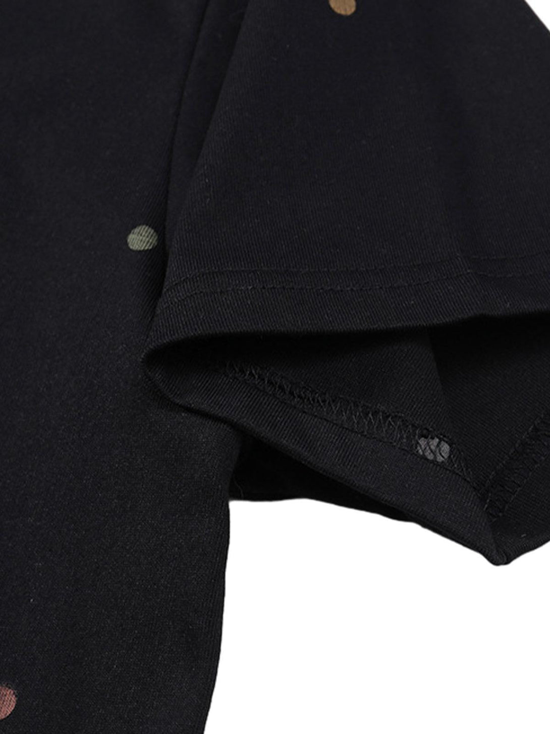 Detailed view of TALISHKO's black t-shirt sleeve featuring colorful polka dots for a playful style.