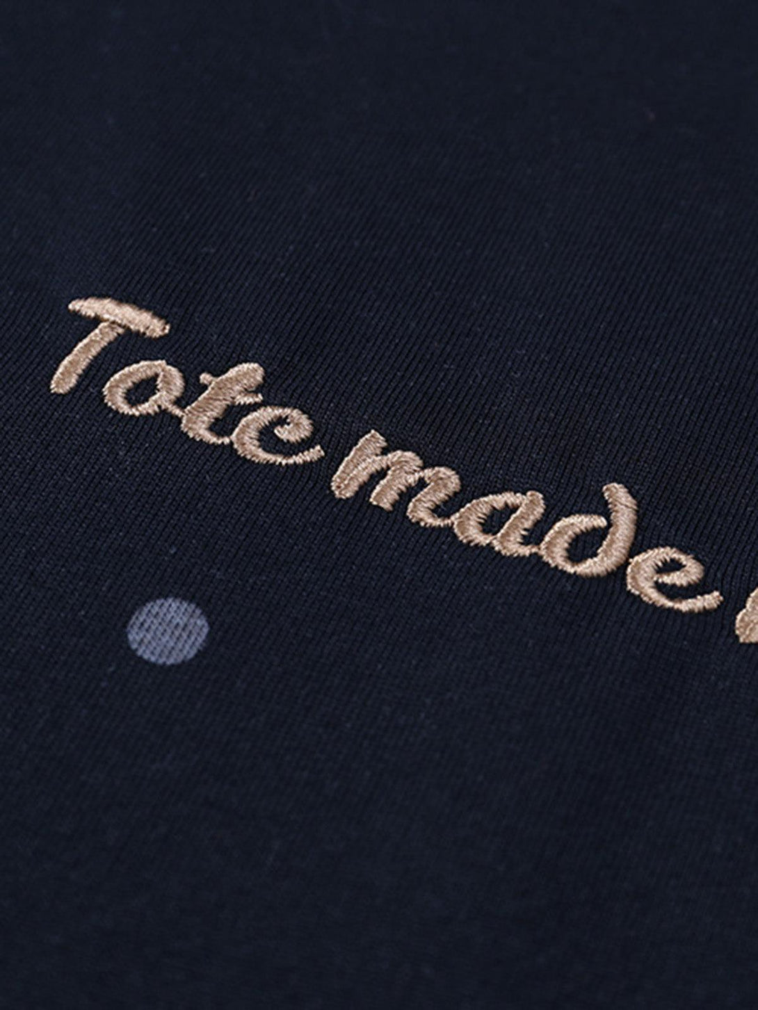 Intricate look at TALISHKO's embroidery detail on a navy t-shirt, adding a stylish touch.